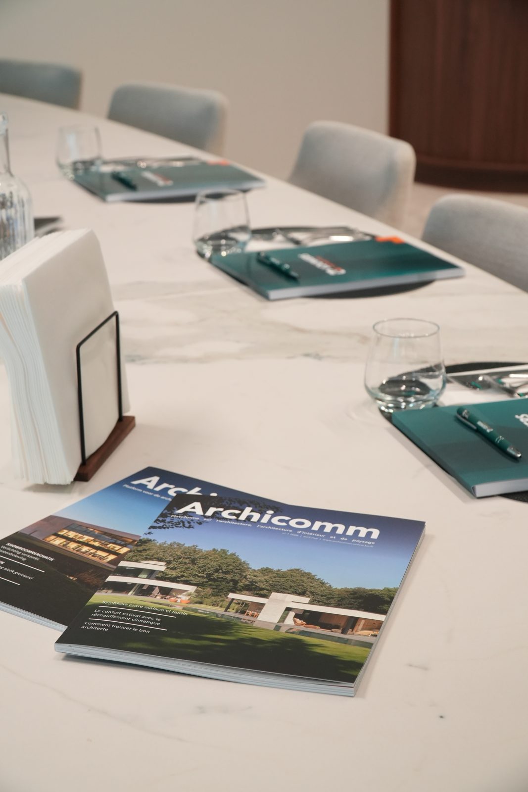 Archicomm-magazines en notitieboekjes klaargelegd op de vergadertafel